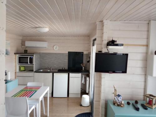a kitchen with a table and a tv on a wall at AGREABLE PETIT CHALET in Camarsac