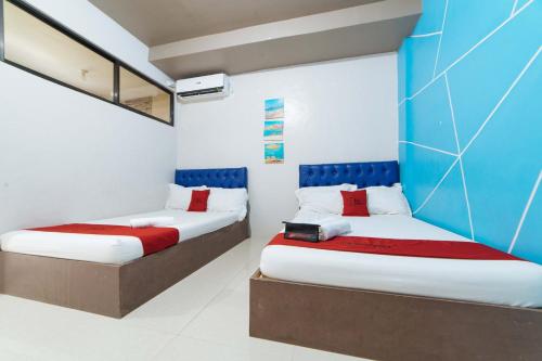 two beds in a room with blue and white walls at RedDoorz @ Aparente Gensan in General Santos