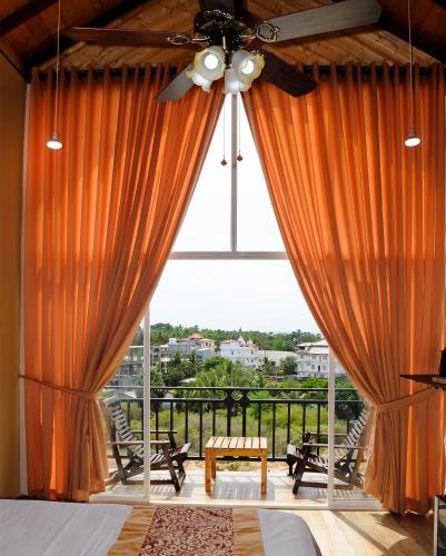 a bedroom with a large window with orange curtains at WoodyCrest in Trincomalee