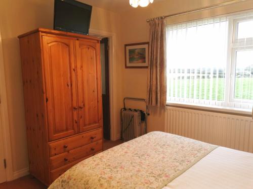 a bedroom with a bed and a dresser at Northumberland Cottage B&B in Eshott