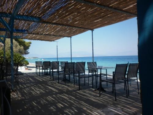 een tafel en stoelen op een strand met uitzicht op de oceaan bij Akri Rooms in Akrata