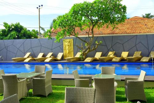 a table and chairs in front of a swimming pool at Ruvisha Beach Hotel in Negombo