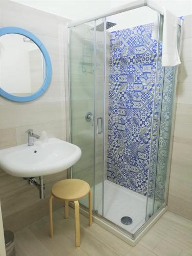 a bathroom with a glass shower with a sink and a stool at AlbaChiara B&B in Gaeta