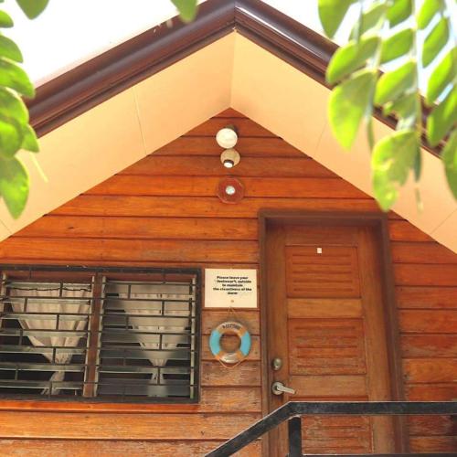 a front door of a wooden building with a window at Happy Camper Hostel in Coron