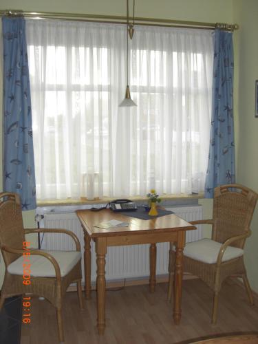 a table and chairs in a room with windows at Hus Nordhauk in Borkum