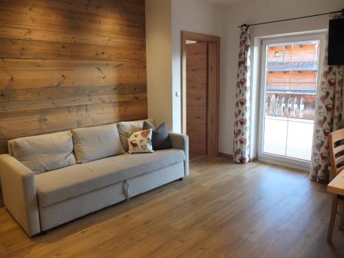a living room with a couch and a wooden wall at Apartment Haus Dahoam in Alpbach