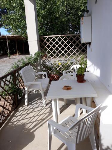 Duas cadeiras brancas e uma mesa num pátio em Agriturismo I Due Pini em Magliano in Toscana