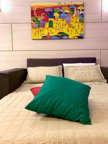 a bed with a green pillow on top of it at Duplex com hidromassagem - Praia do Forte in Praia do Forte