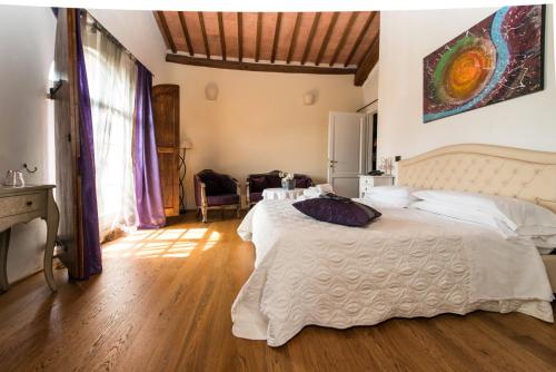 a bedroom with a large white bed and wooden floors at L'Albero Di Gamelì in Chiusi