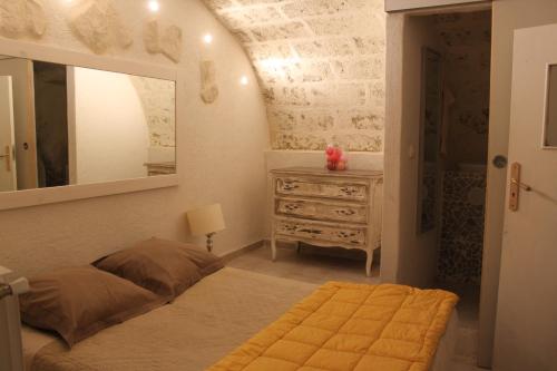 Schlafzimmer mit einem Bett, einer Kommode und einem Spiegel in der Unterkunft maison de village in Saint-Quentin-la-Poterie