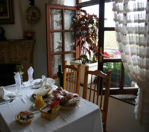 una mesa blanca con comida en una habitación con ventana en Hotel De Borleña, en Borleña