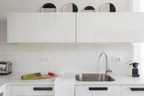 a kitchen counter with a sink and vegetables on a cutting board at The Rambam Residence - By Localz Group in Tel Aviv