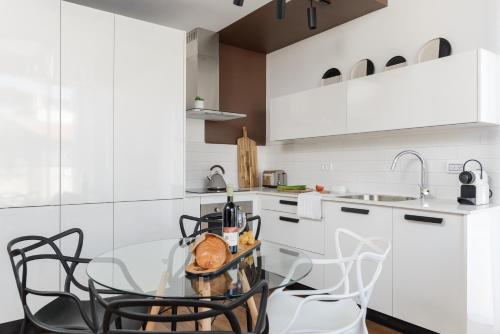 a white kitchen with a glass table and chairs at The Rambam Residence - By Localz Group in Tel Aviv