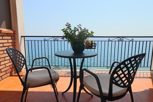 a table with two chairs and a plant on a balcony at Park Hotel Silemi in Letojanni