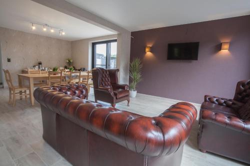 a living room with a leather couch and a table at B&B D'Hollehoeve in Heist-op-den-Berg