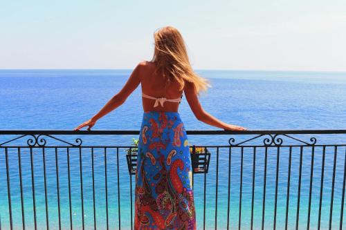 une femme debout sur un balcon donnant sur l'océan dans l'établissement Park Hotel Silemi, à Letojanni