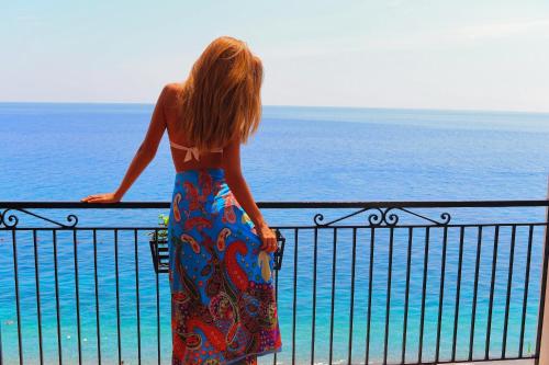 a woman standing on a balcony looking at the ocean at Park Hotel Silemi in Letojanni