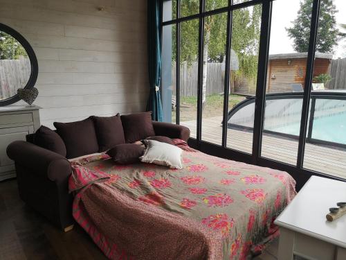 ein Schlafzimmer mit einem Bett und einem großen Fenster in der Unterkunft La Cabane Bois des Roses in Les Rosiers