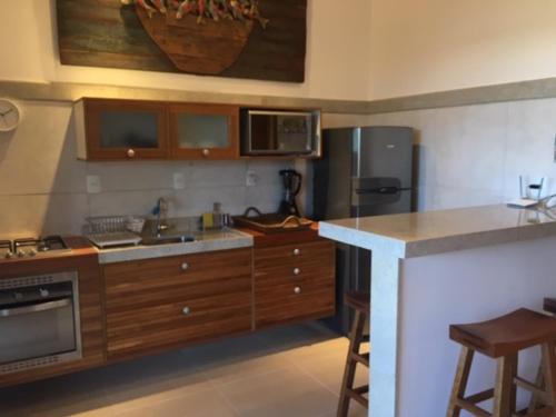 a kitchen with a sink and a stove and a refrigerator at Praia do Forte Apartamento Fantástico in Praia do Forte