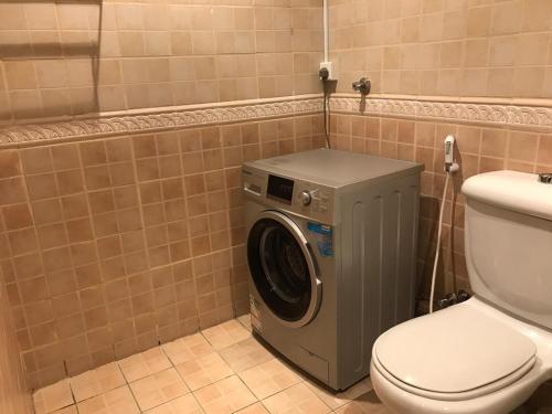 - un lave-linge dans une salle de bains à côté des toilettes dans l'établissement Ajwaa Suites, à Djeddah