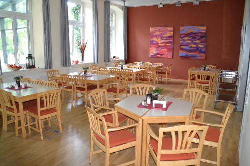 una sala da pranzo con tavoli, sedie e finestre di Christian Jensen Kolleg und Gästehäuser a Breklum