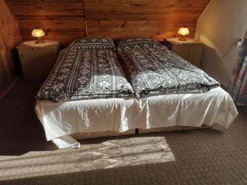 a bed in a room with two nightstands and two lamps at Chaty Javorina in Javorina