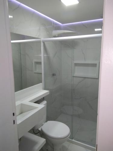 Un baño blanco con inodoro y ducha. en WB Apto condomínio Jubiabá, en Olivença