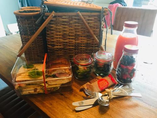 a table with a basket and a sandwich and jars of jam at Bed & Breakfast "aan de banis" in Rijssen