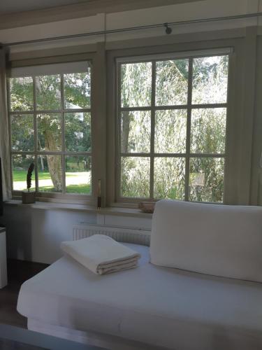 a white bed with two towels on it in front of windows at B&B Saense huisje in Assendelft