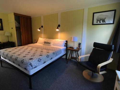 a bedroom with a bed and a chair at Snowdon Chalet Motel in Londonderry