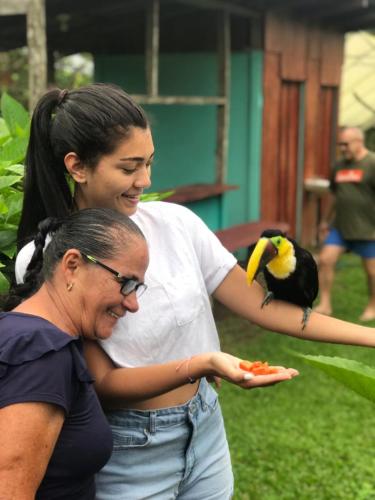 a woman standing next to a woman with a bird on her arm at Posada Río Celeste La Amistad in Rio Celeste