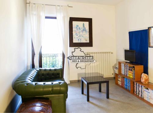B&B Coast to Coast في Armento: غرفة معيشة مع أريكة جلدية خضراء وتلفزيون