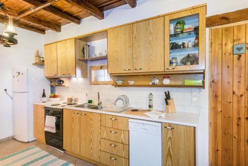 a kitchen with wooden cabinets and a white refrigerator at ARADENA TRADITIONAL House 2 in Arádhaina
