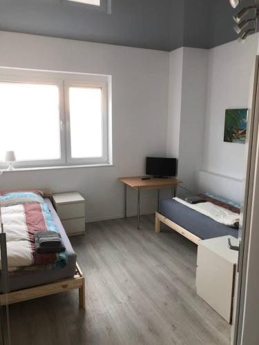 a bedroom with a bed and a desk and a television at Zimmer 5 in Alzenau in Unterfranken