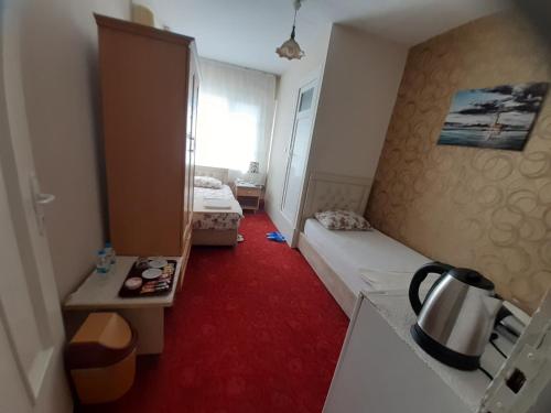 Habitación pequeña con cama y alfombra roja. en SAYDAM OTEL en Seyhan