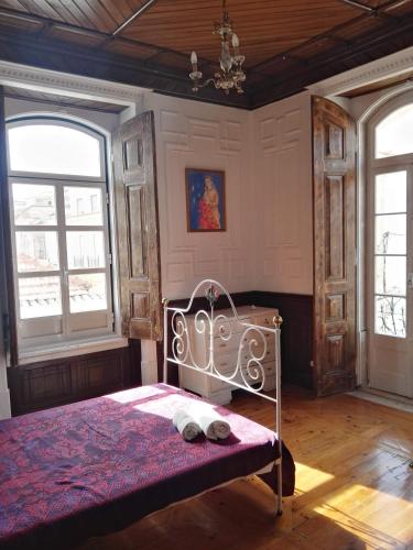 a bedroom with a bed and two windows at Casa da Rainha in Azambuja