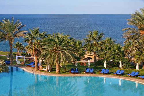 
a beach with palm trees and palm trees at Azia Resort & Spa in Paphos
