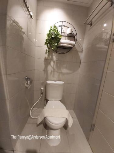 a bathroom with a toilet with a plant on the wall at The Paneya@Anderson Apartment in Surabaya