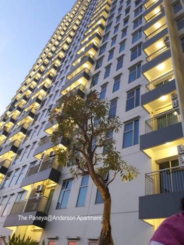 a tall building with a tree in front of it at The Paneya@Anderson Apartment in Surabaya