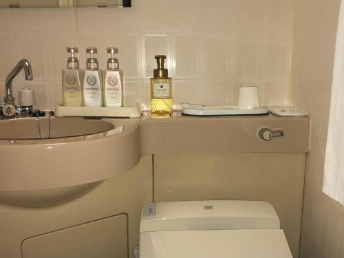 a bathroom with a toilet and a sink and bottles of alcohol at Hotel Ikeda in Nagasaki