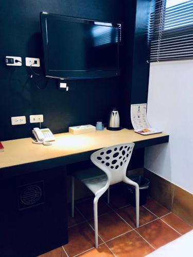 a desk with a computer monitor and a chair at Lai Chi Te Hotel in Tainan