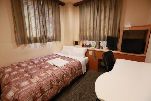 Habitación de hotel con cama, escritorio y TV. en Hotel Ikeda, en Nagasaki