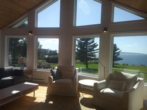 a living room with two chairs and a large window at Private Waterfront Luxury on the Bras D'Or Lake in Sydney Forks