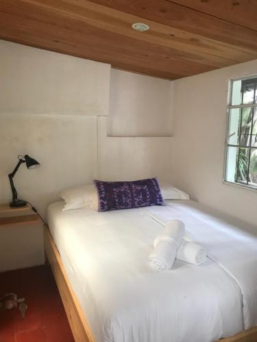 a white bed with two pillows on it in a room at Maya Papaya in Antigua Guatemala
