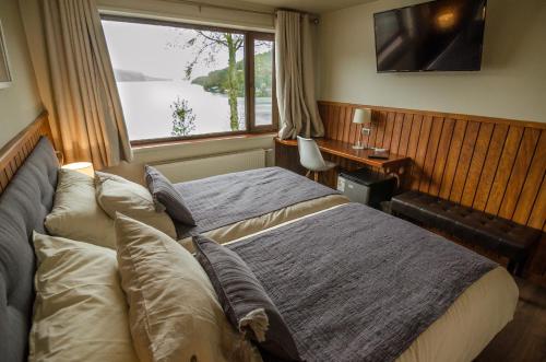 a bedroom with a bed and a window and a desk at Hotel Boutique Cutipay in Valdivia