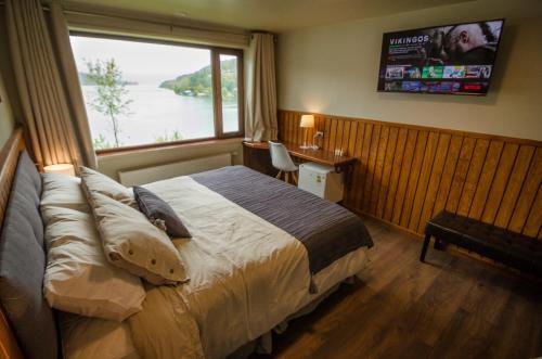 a bedroom with a bed with a window and a television at Hotel Boutique Cutipay in Valdivia