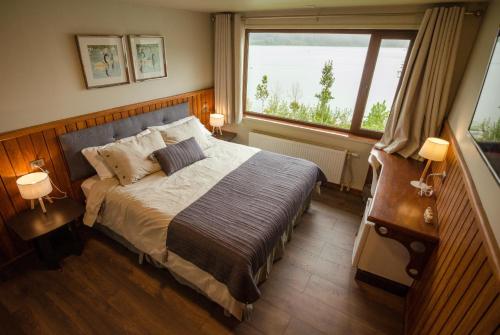 a bedroom with a bed and a large window at Hotel Boutique Cutipay in Valdivia