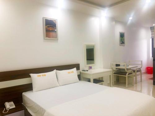 1 dormitorio con cama blanca y mesa en Cosy Star Apartment and Motel, en Hai Phong