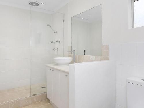 a white bathroom with a sink and a shower at Amalfi Beach House in Gerringong