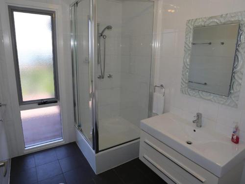 a white bathroom with a shower and a sink at Brilliant Ocean Views in Gerroa